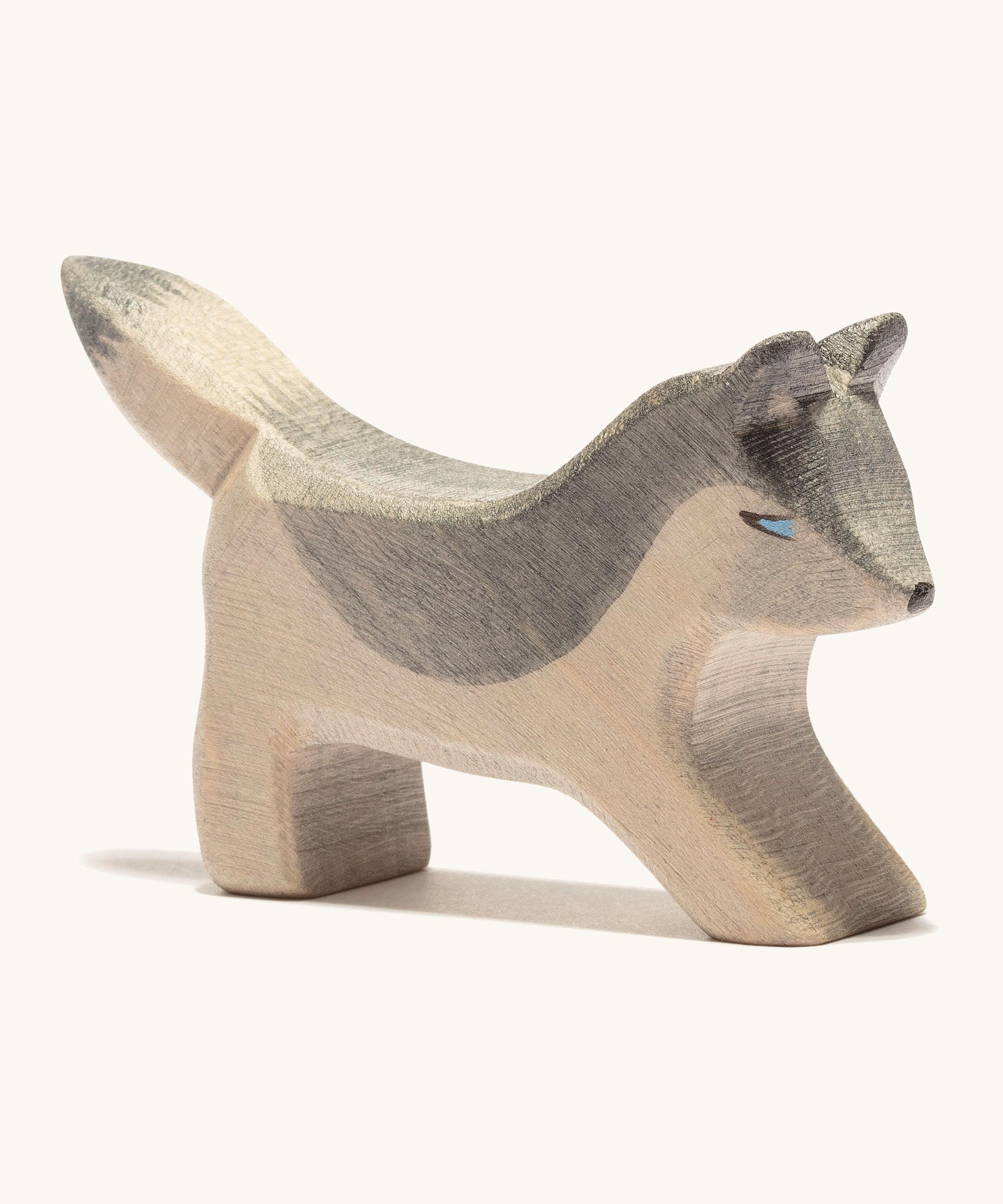 A small wooden Ostheimer wolf playing, on a cream background.