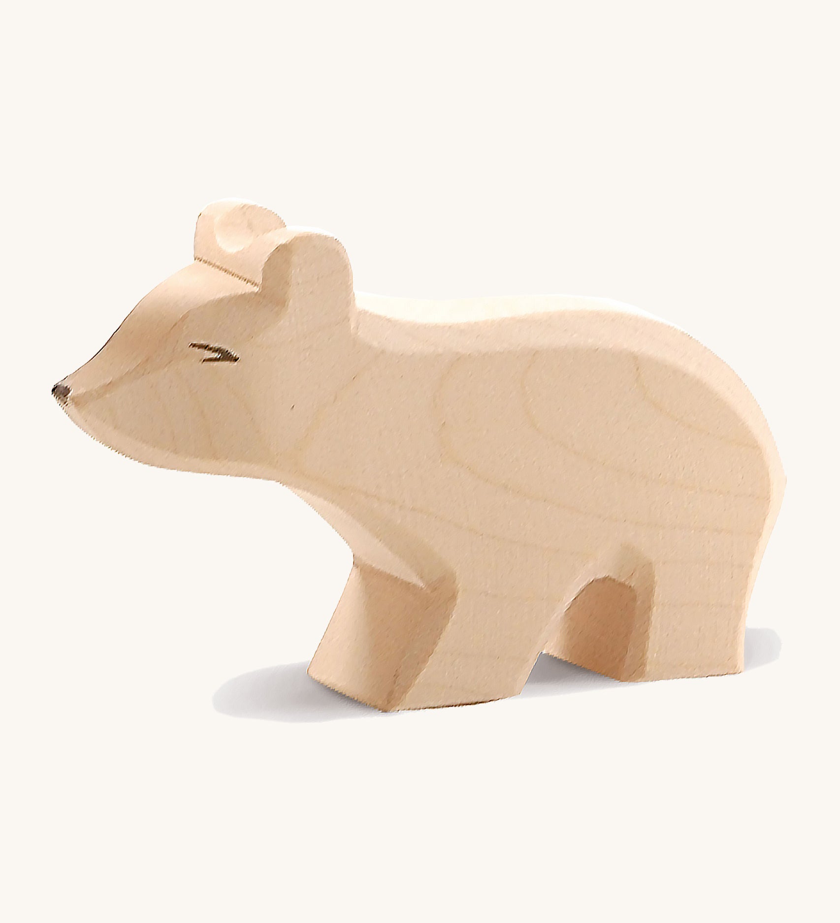 A small wooden Ostheimer polar bear figure with a long neck on a cream background.