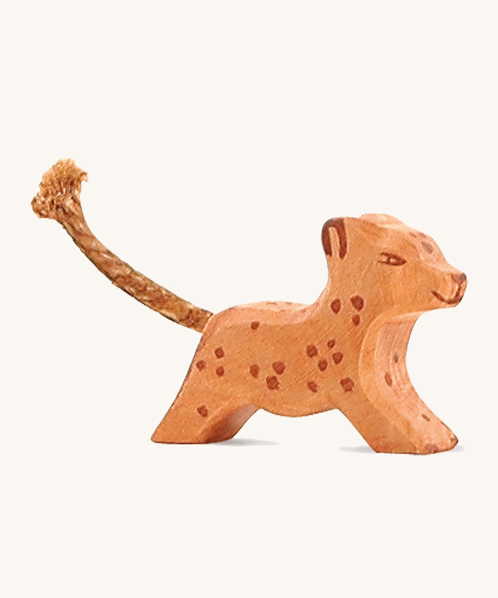 A small running wooden Ostheimer leopard figure on a cream background.