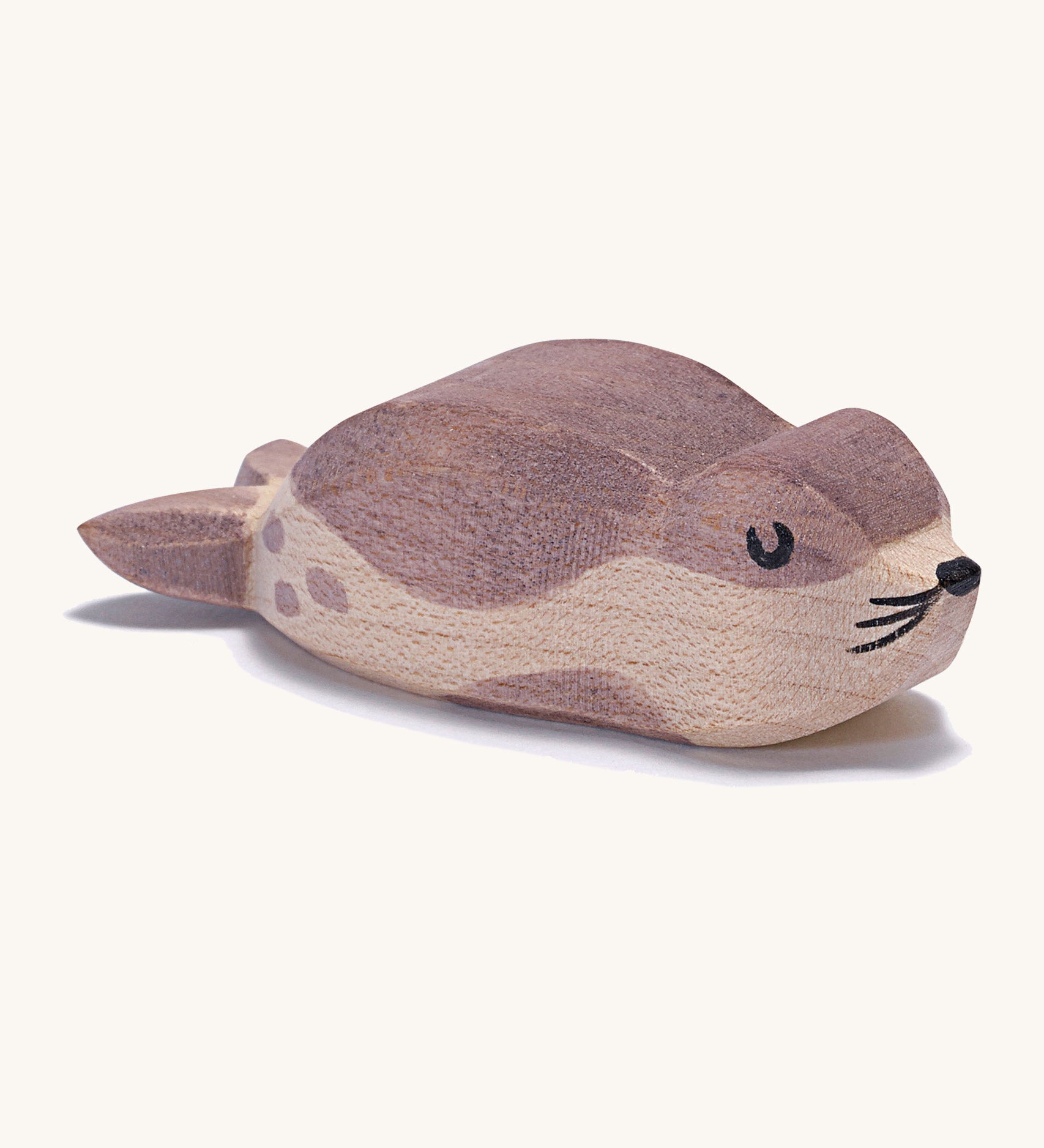 A small wooden Ostheimer sea lion figure on a cream background.