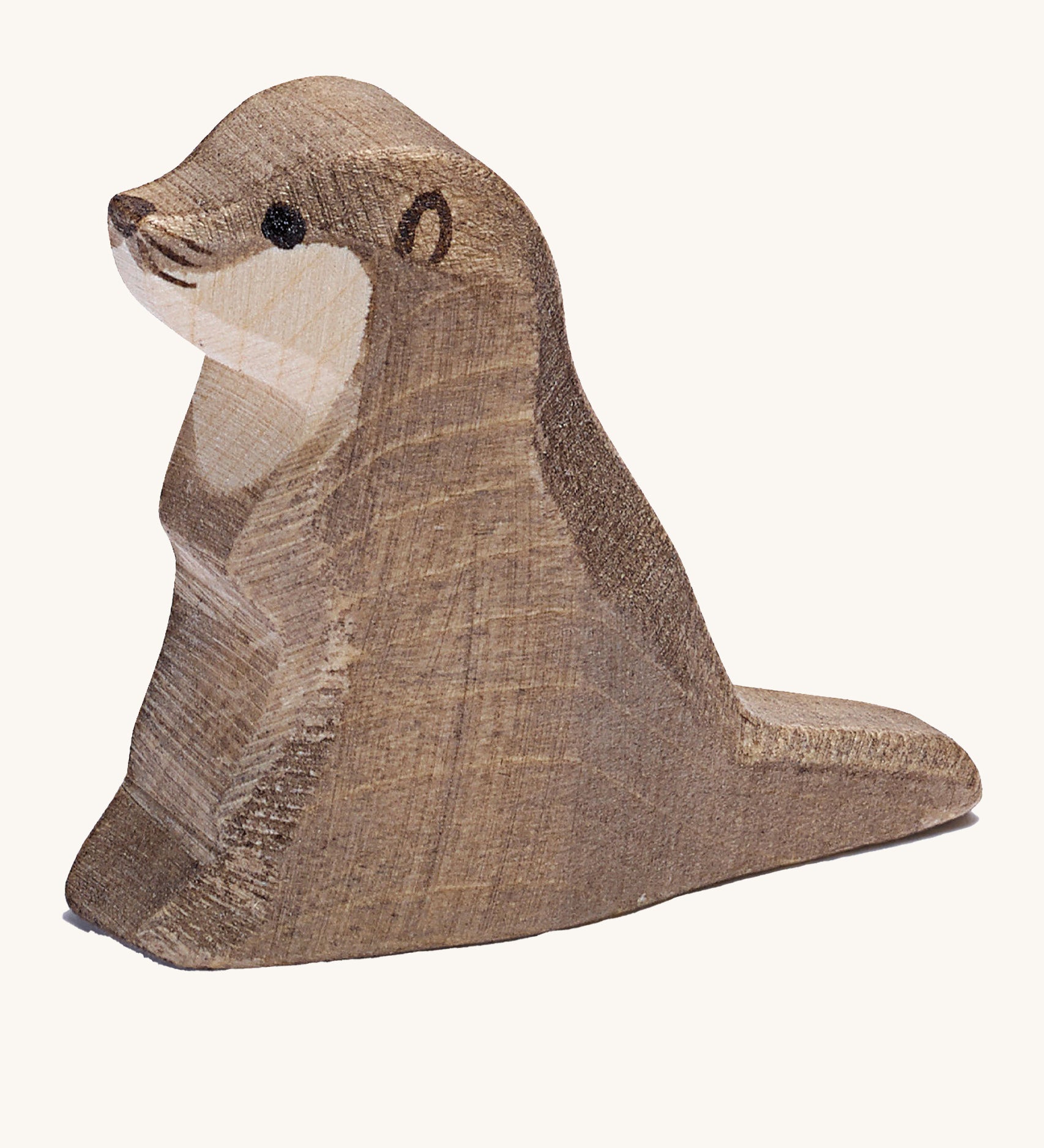 A small wooden Ostheimer sea otter figure on a cream background.