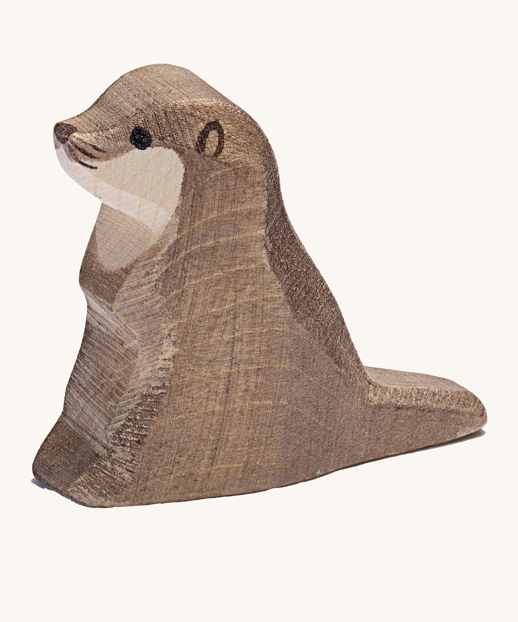 A small wooden Ostheimer sea otter figure on a cream background.