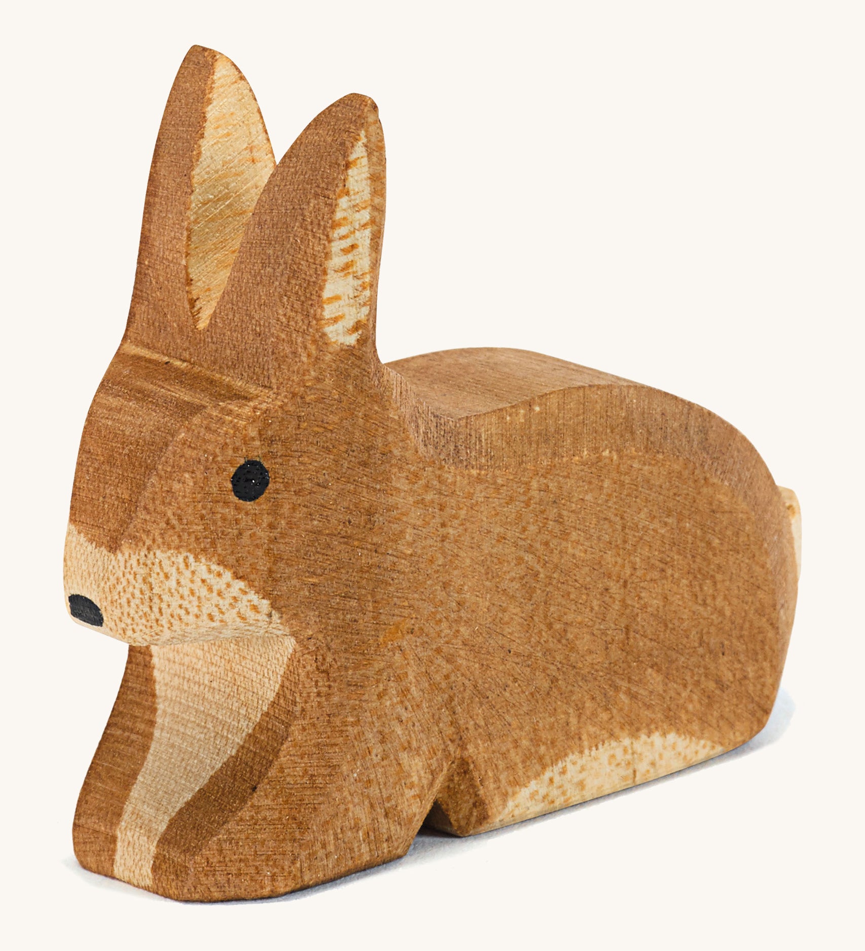 A small brown spotted sitting Ostheimer rabbit figure on a cream background.