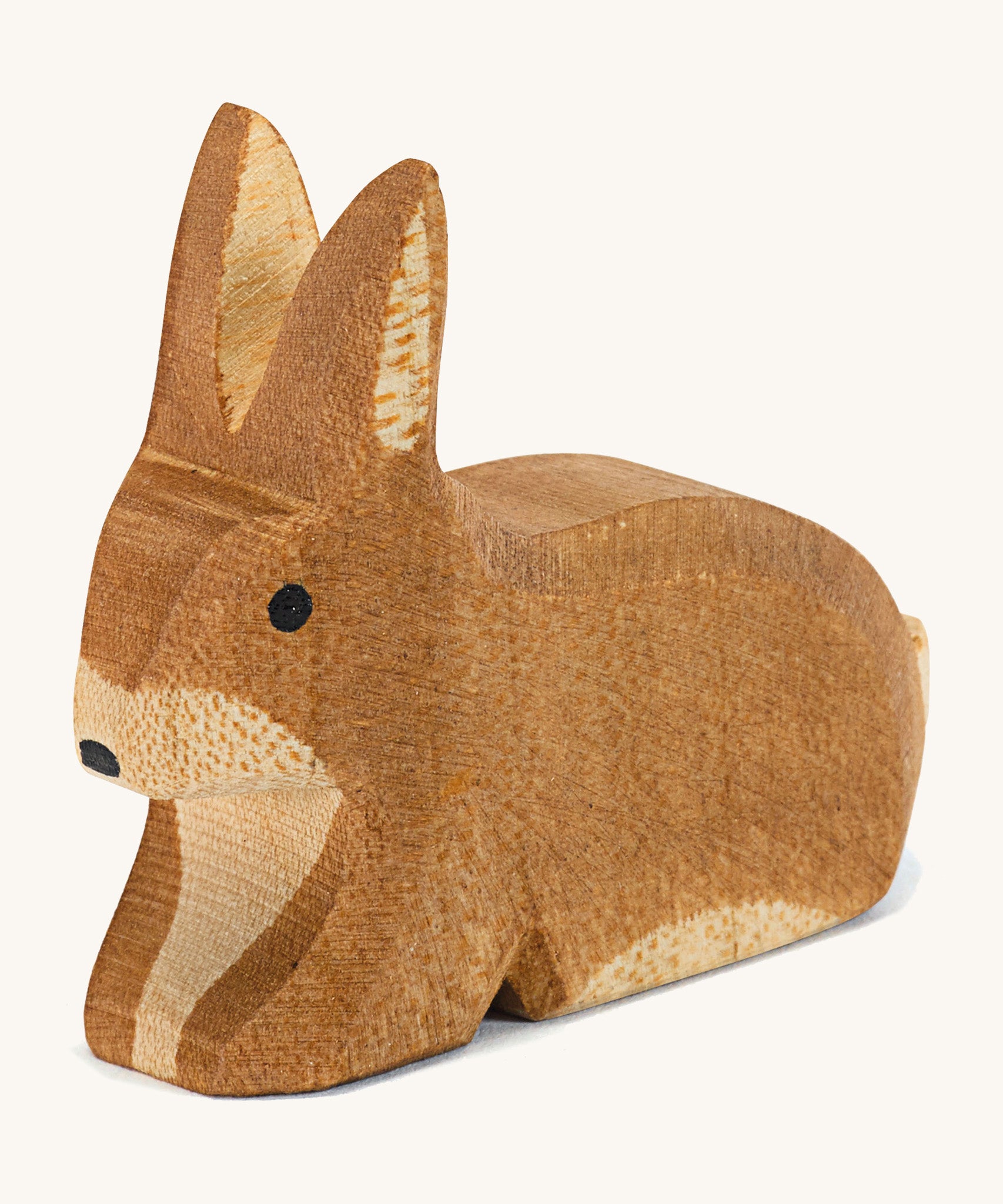 A small brown spotted sitting Ostheimer rabbit figure on a cream background.