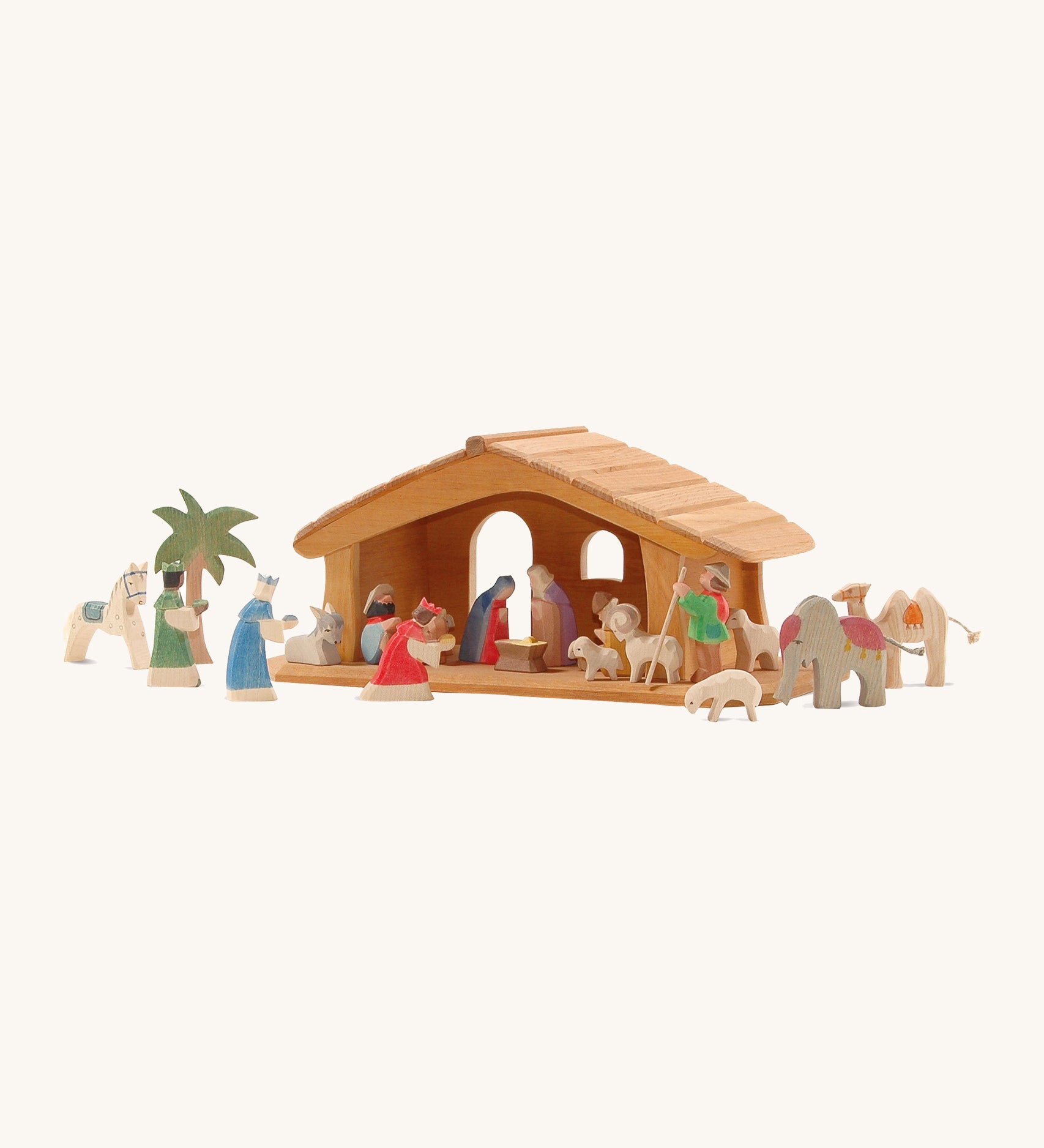 A small wooden Ostheimer stable with the Ostheimer nativity figures around it on a cream background.