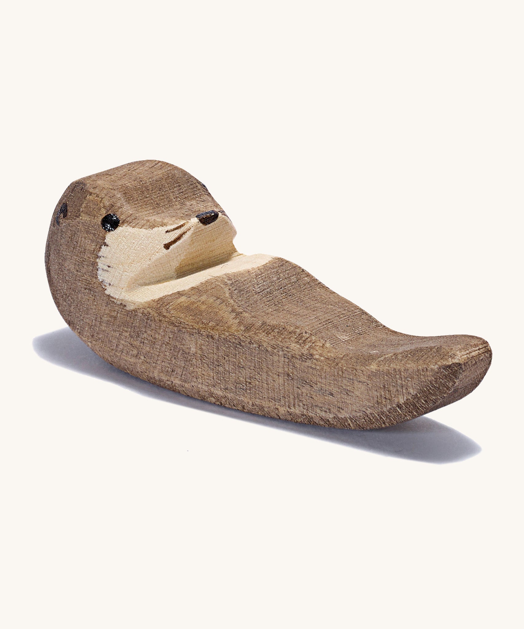 A small wooden Ostheimer swimming otter figure on a cream background.