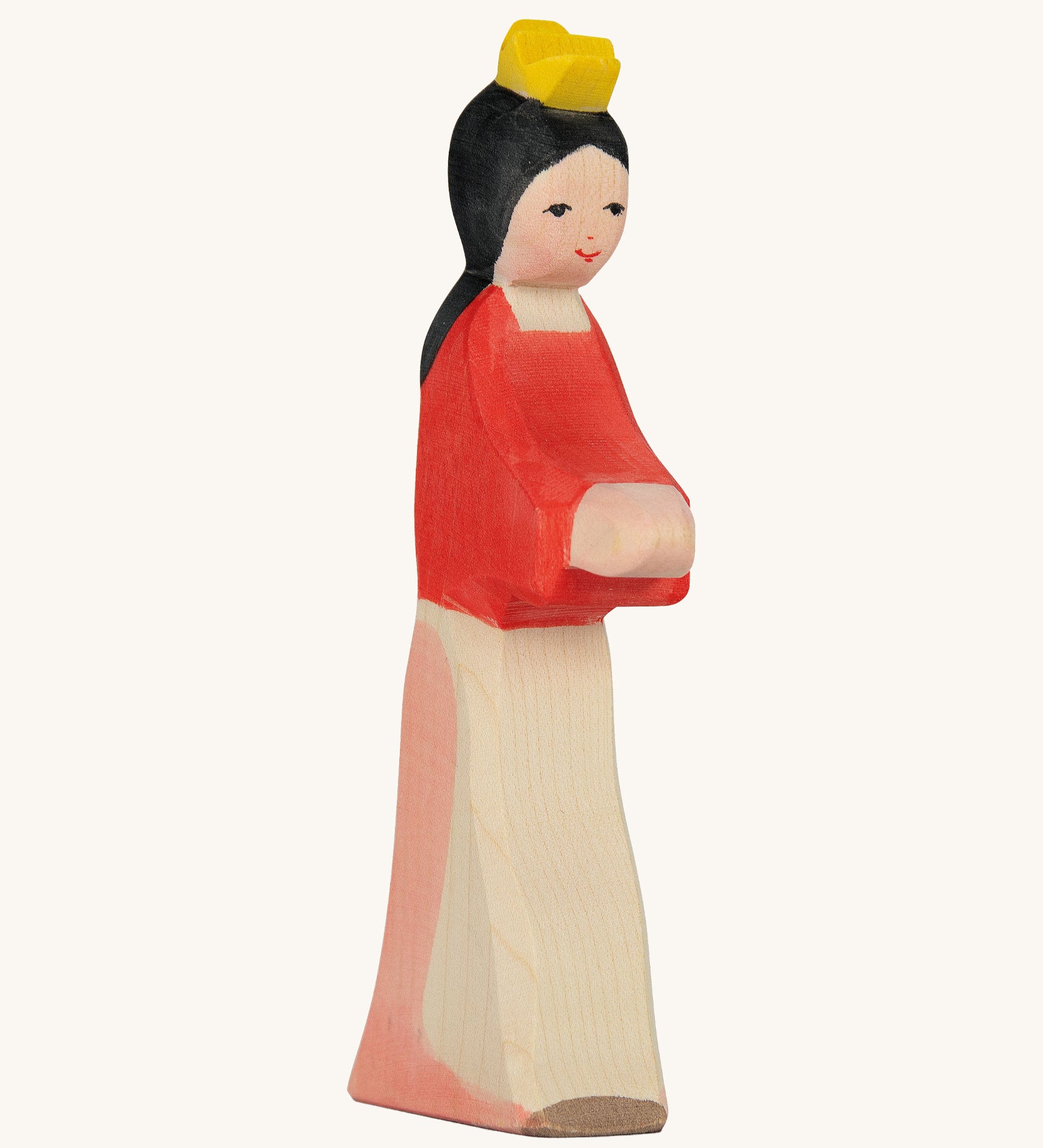 A wooden Ostheimer wooden snow white figure wearing a white and pink skirt, a red top and a yellow crown on a cream background.