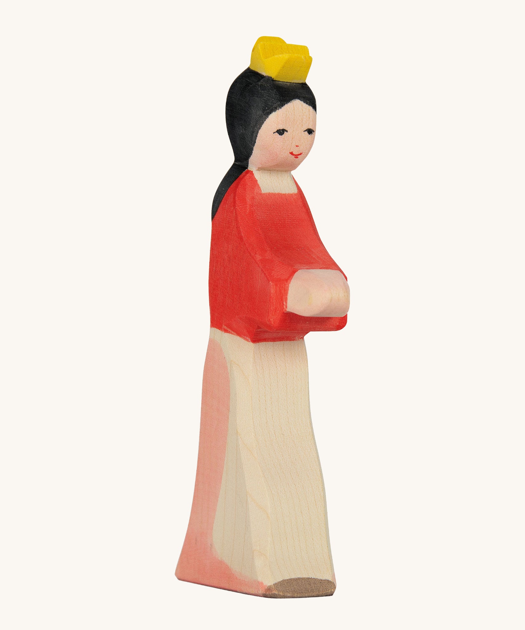 A wooden Ostheimer wooden snow white figure wearing a white and pink skirt, a red top and a yellow crown on a cream background.