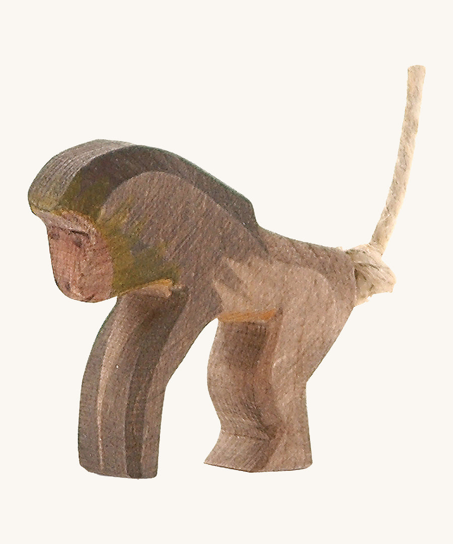 A wooden standing Ostheimer baboon figure on a cream background.