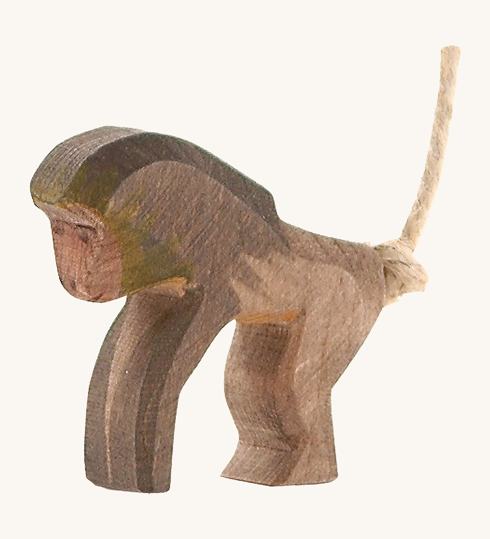 A wooden standing Ostheimer baboon figure on a cream background.