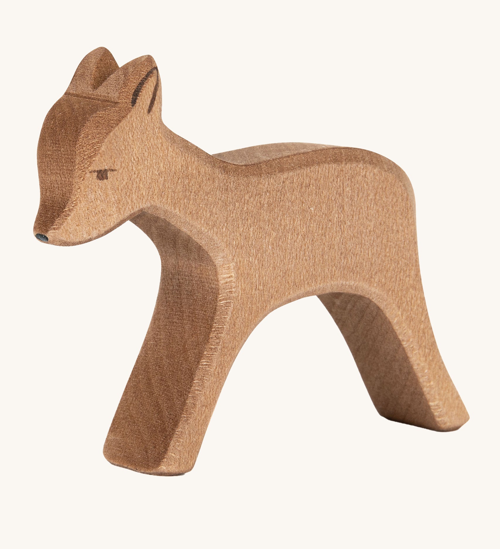 A wooden standing Ostheimer deer figure on a cream background.