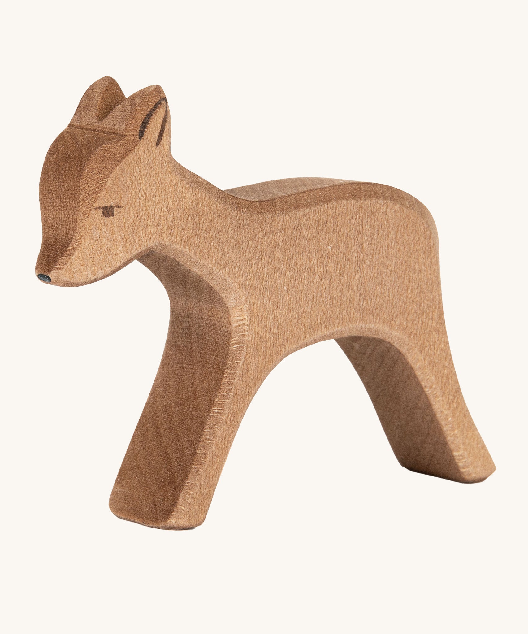 A wooden standing Ostheimer deer figure on a cream background.