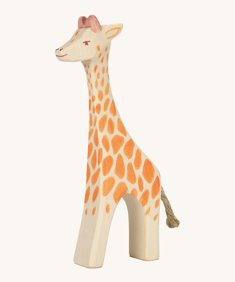 A wooden standing Ostheimer giraffe figure on a cream background.