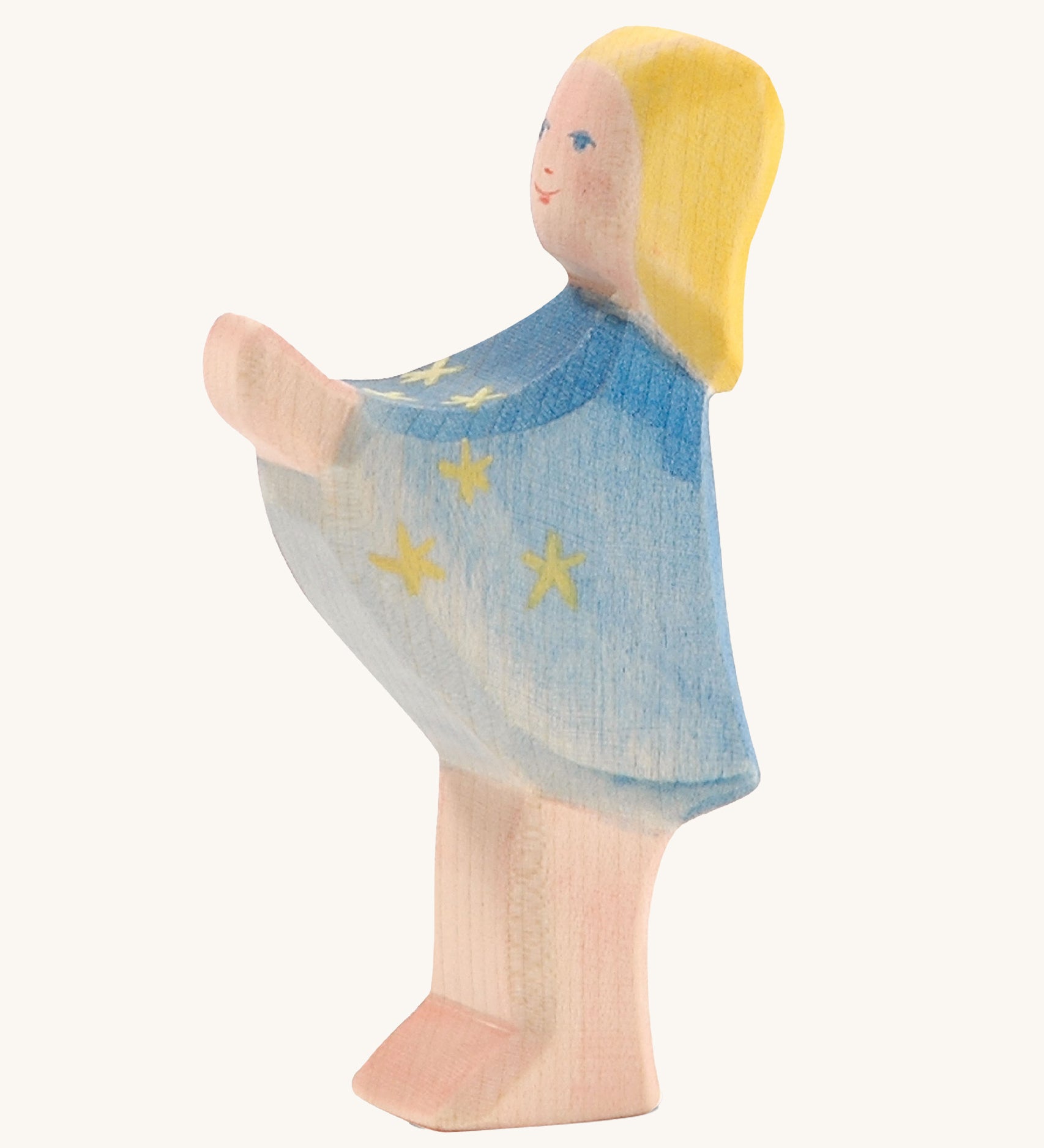 A wooden Ostheimer star taler figure wearing a blue cape with gold stars on a cream background.