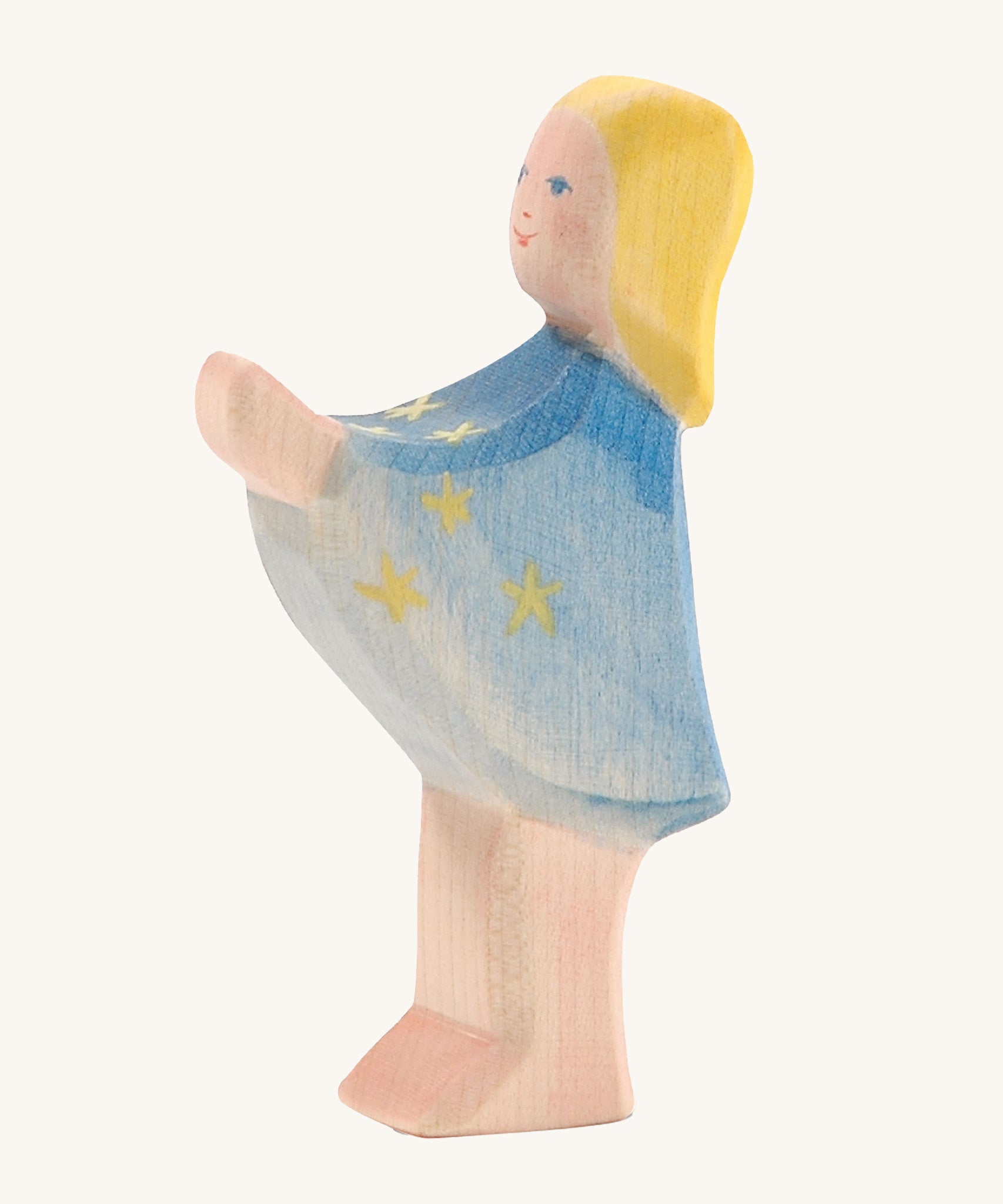 A wooden Ostheimer star taler figure wearing a blue cape with gold stars on a cream background.