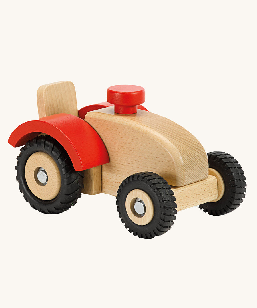 Ostheimer Wooden Tractor toy on a plain background. The tractor has red wheel arches and black rubber tyres. 