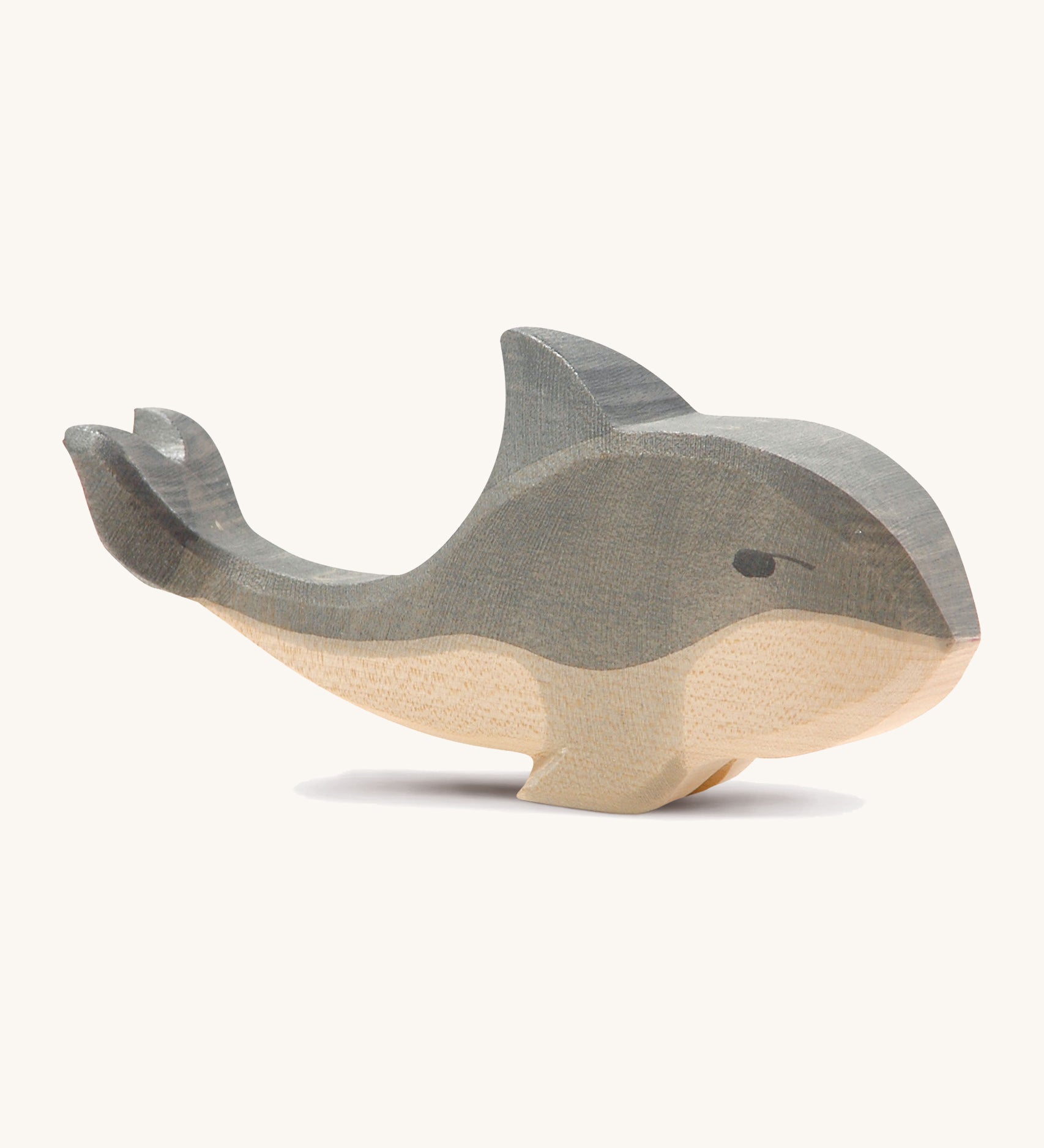 A wooden Ostheimer whale figure on a cream background.