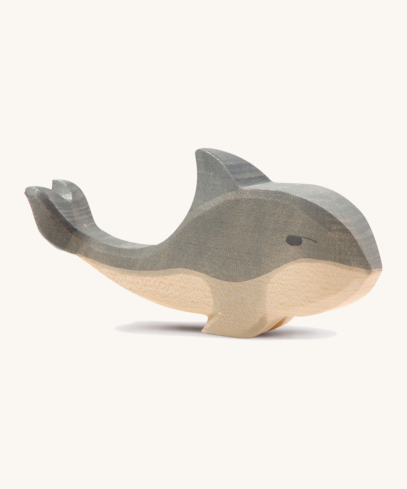 A wooden Ostheimer whale figure on a cream background.