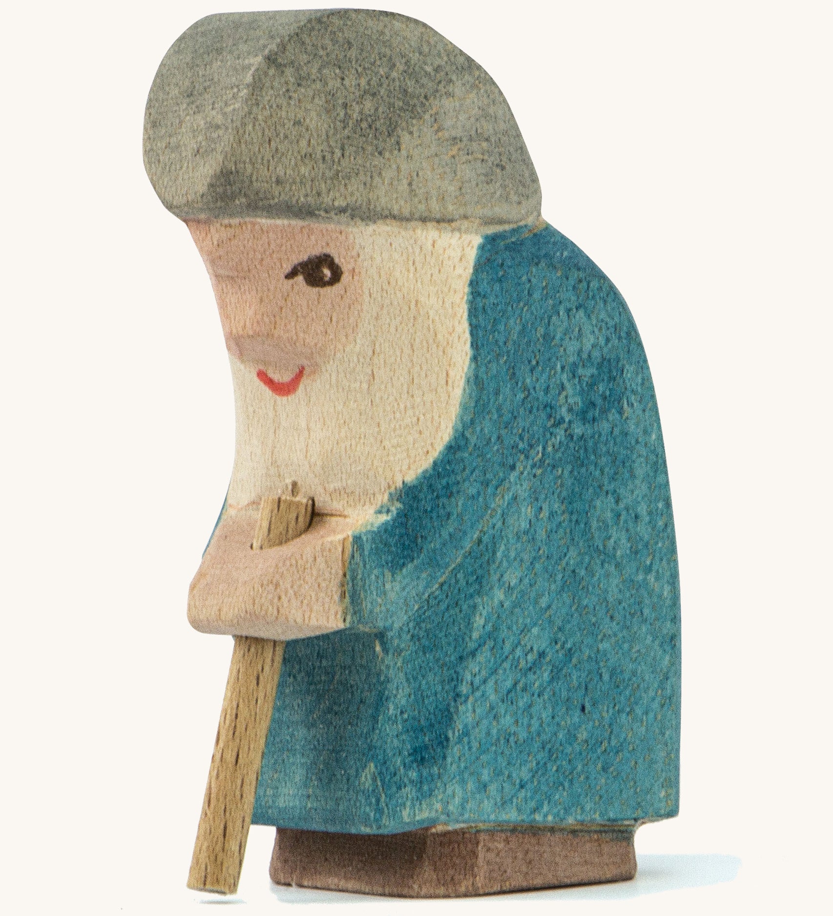 A wooden Ostheimer Willi dwarf figure wearing a blue coat and a grey hat holding a wooden staff on a cream background.