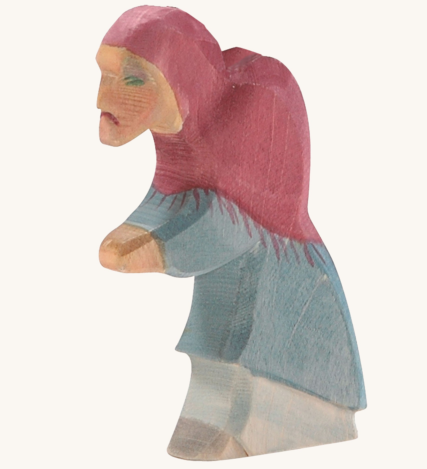 A wooden Ostheimer witch figure wearing a blue outfit and a purple hood on a cream background.