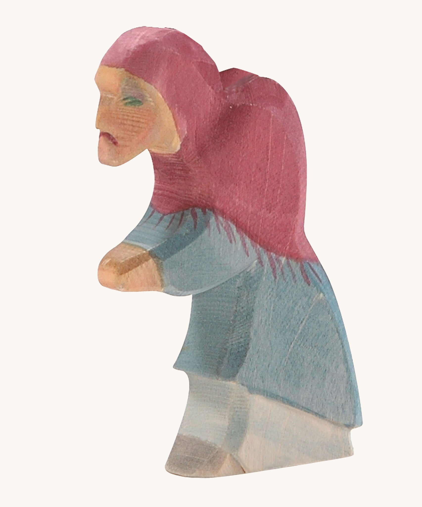 A wooden Ostheimer witch figure wearing a blue outfit and a purple hood on a cream background.