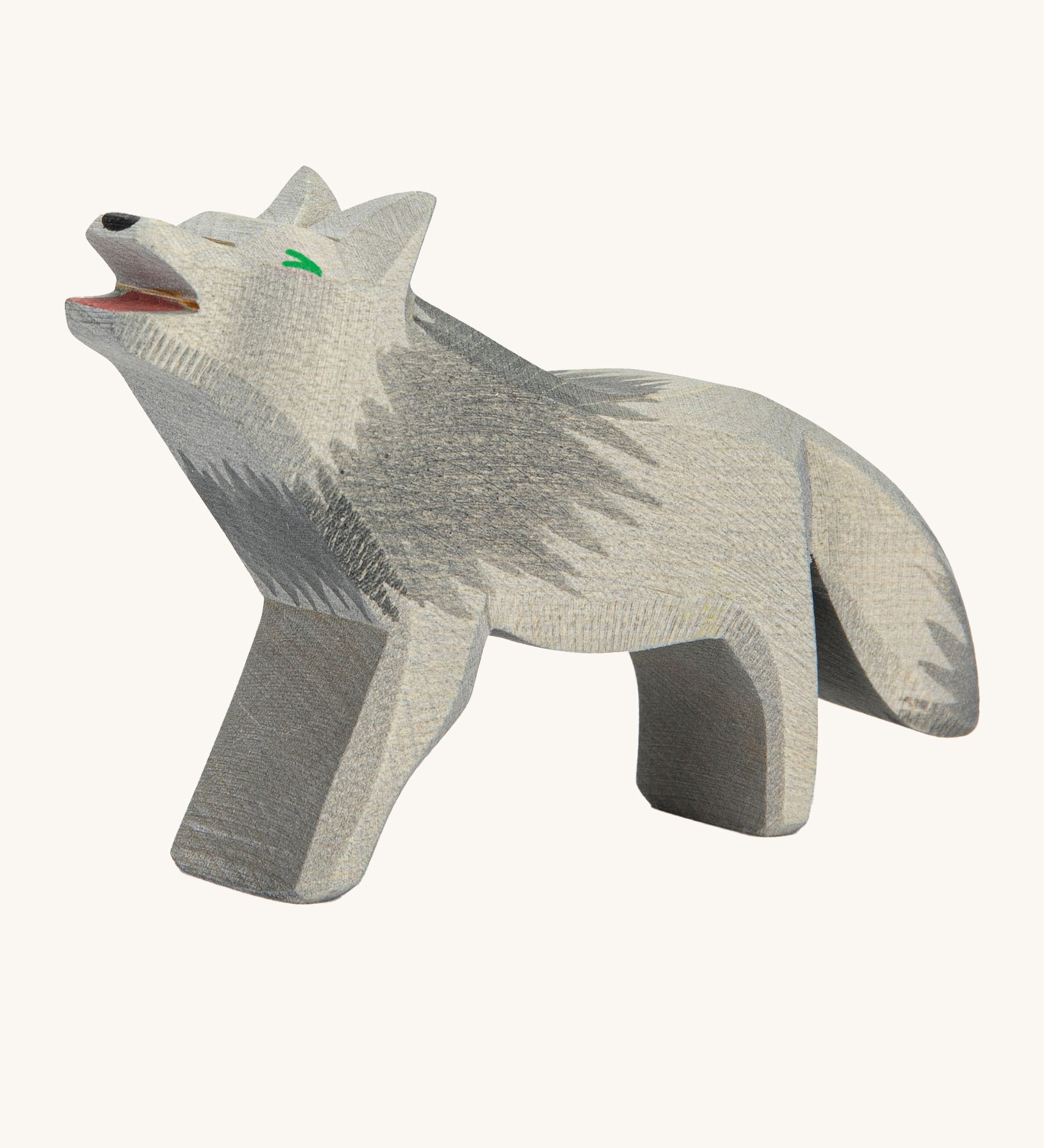 A wooden howling Ostheimer grey wolf figure on a cream background.