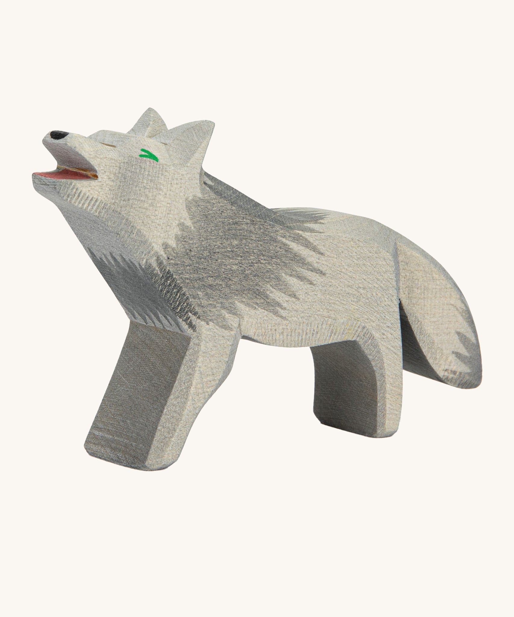 A wooden howling Ostheimer grey wolf figure on a cream background.