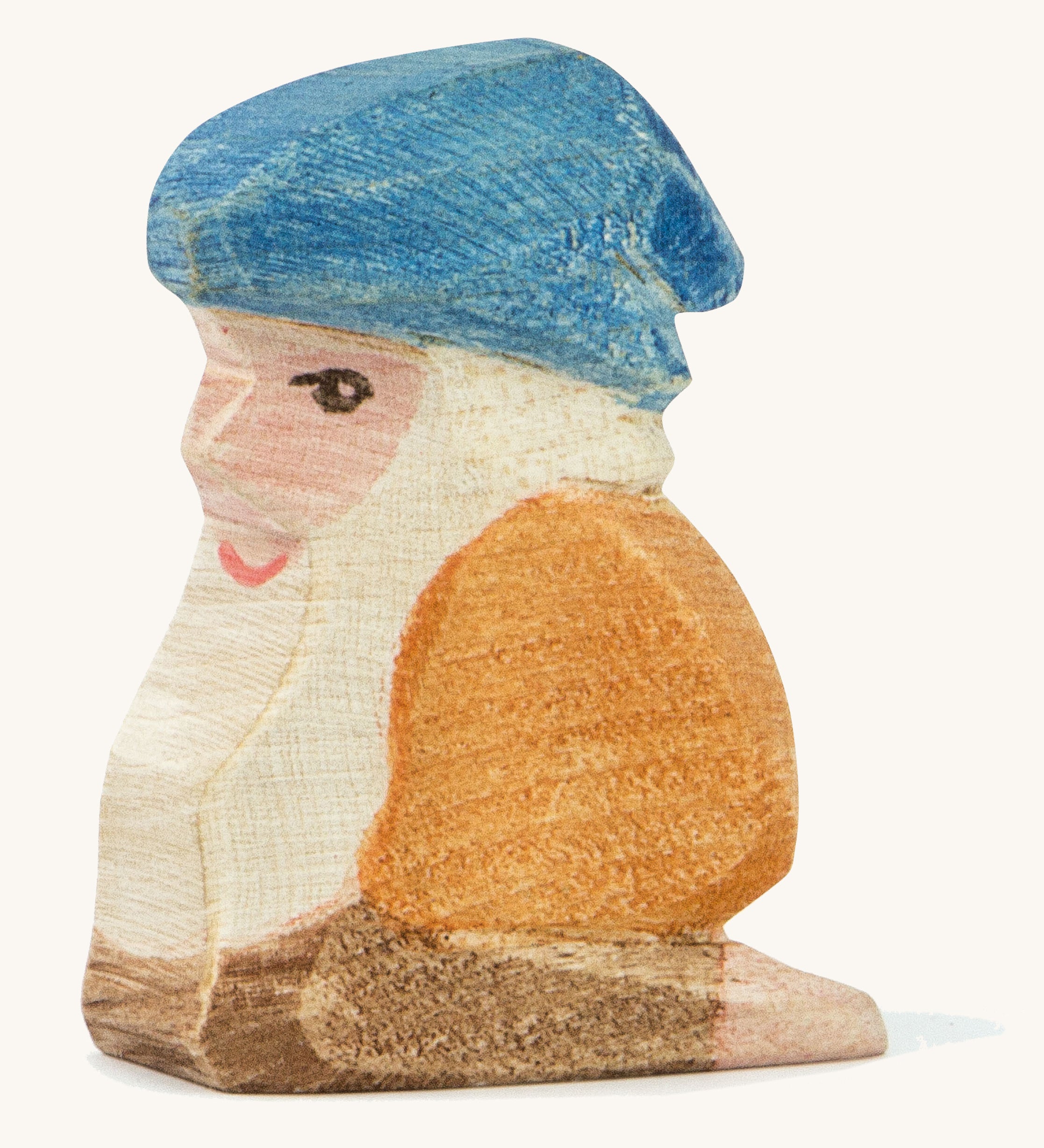 A Ostheimer wooden Xaver dwarf figure wearing a orange top and a blue hat on a cream background.