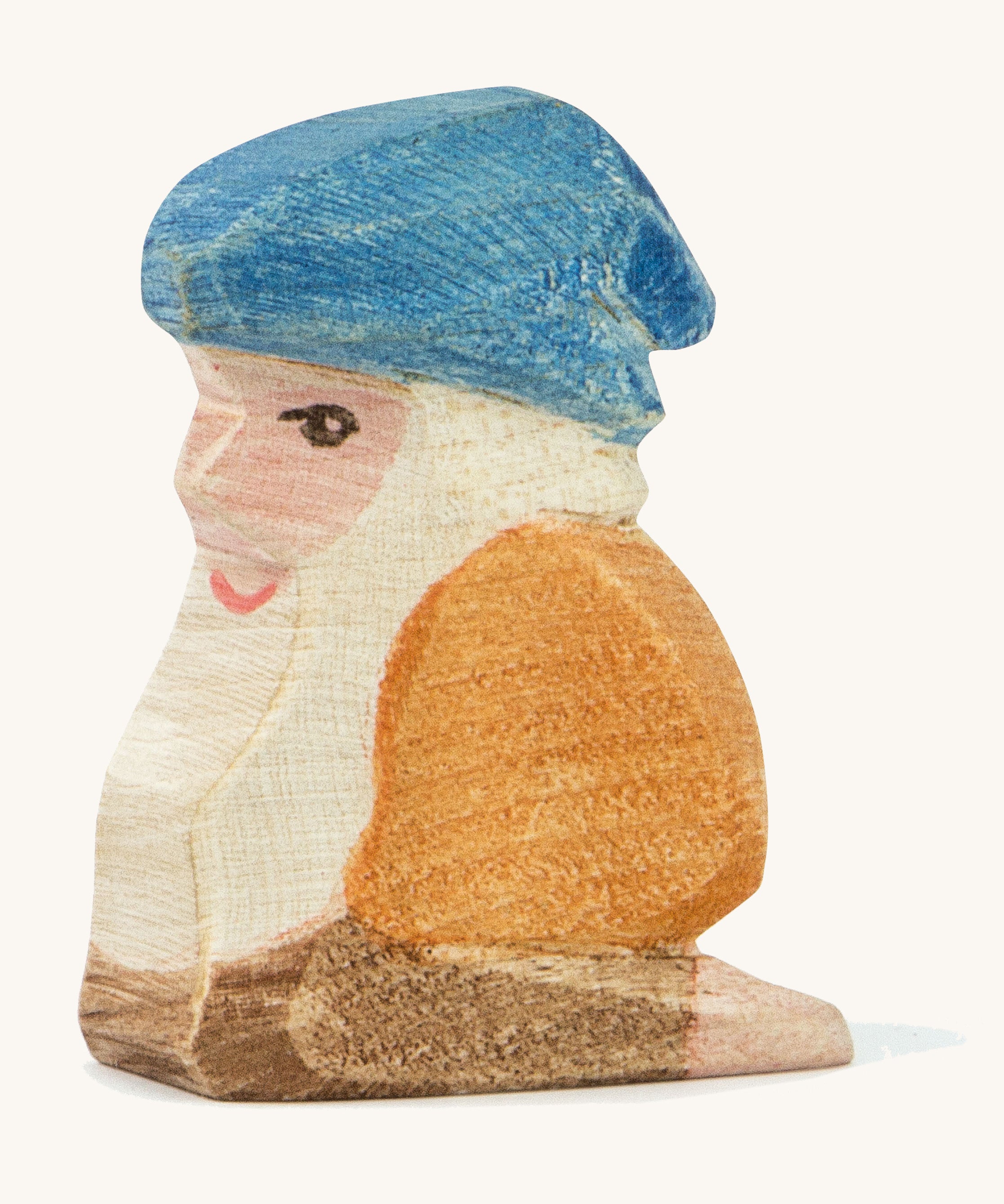 A Ostheimer wooden Xaver dwarf figure wearing a orange top and a blue hat on a cream background.