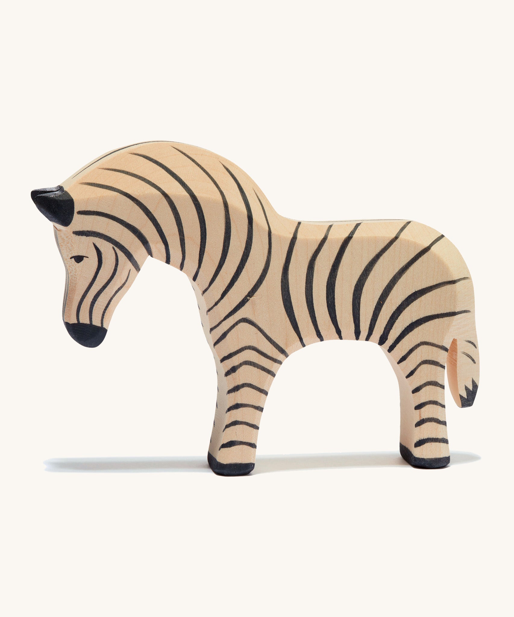 A wooden Ostheimer zebra figure on a cream background.