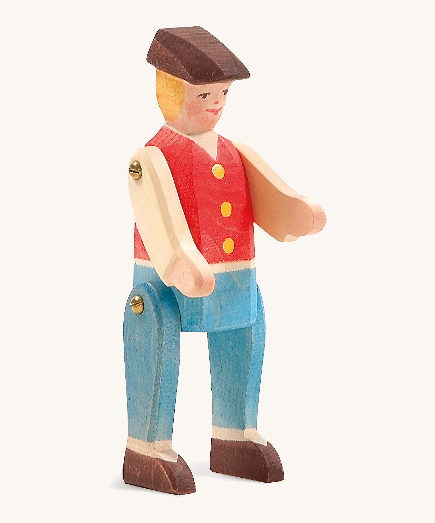 A wooden Ostheimer rider figure wearing a red waistcoat, blue trousers and a brown hat on a cream background.