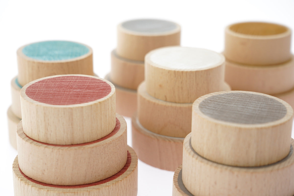 Close up of the Papoose handmade coloured wooden earth coins stacked in towers on a white background