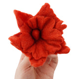 Close up of a hand holding a Papoose plastic-free soft felt flower toy on a white background