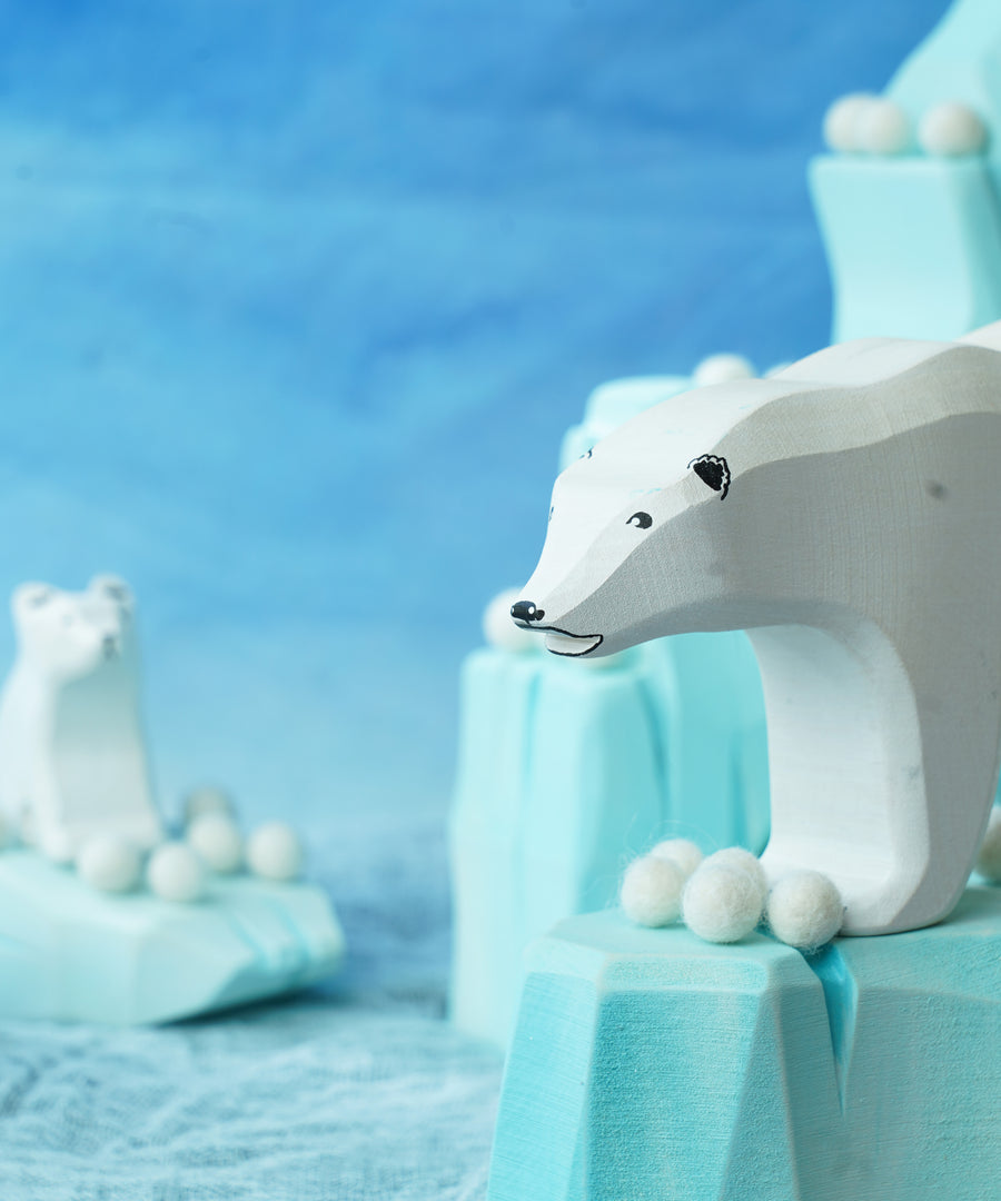 Felted white pom poms on wooden ice rock figures with wooden polar bear figures standing on the ice rocks.