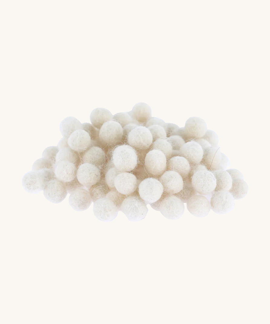 white felted pom poms piled up on a cream backround