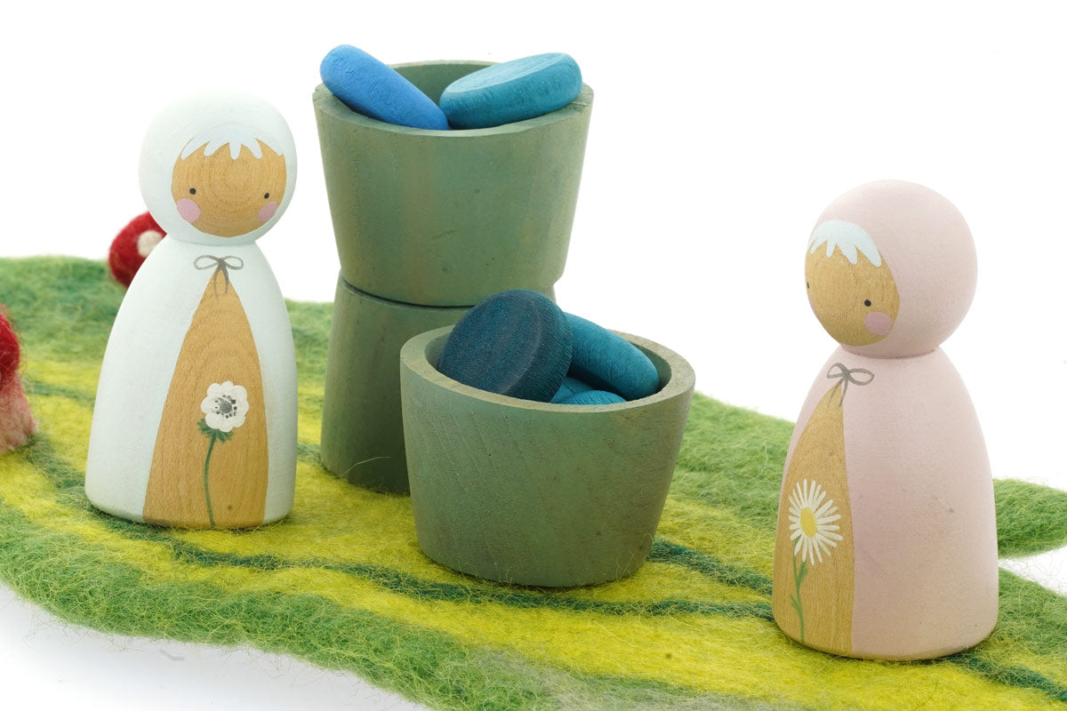 Papoose small wooden earth bowls on a green playmat next to some Peepul wooden figures