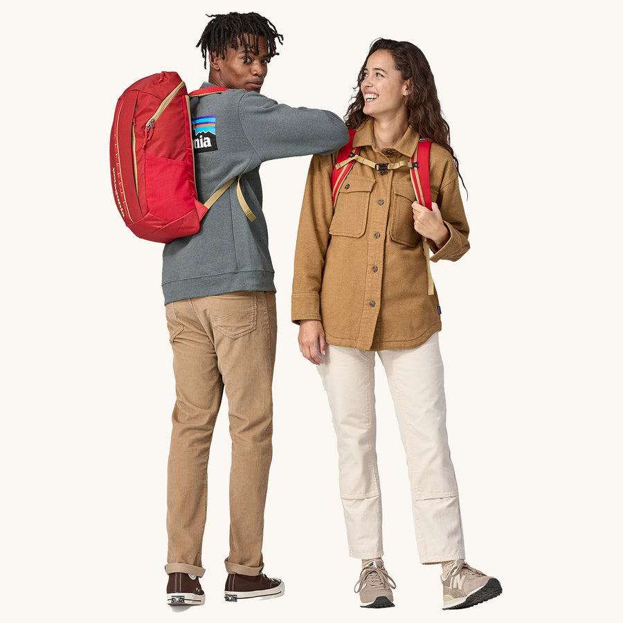 Two people wearing Patagonia Recycled Black Hole Backpack 25L in Touring Red showing front and rear view on a cream background 