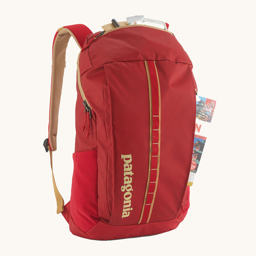 Patagonia Recycled Black Hole Backpack 25L in Touring Red with a reusable water bottle in the mesh side pocket on a cream background