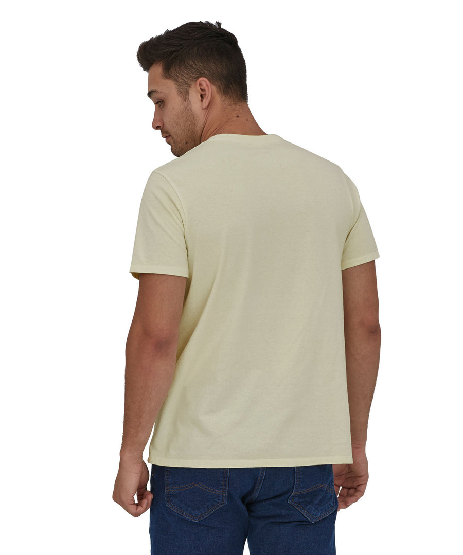 A man wearing a Patagonia Adult Fitz Roy Icon Responsibili-Tee in a Birch White colour stood in front of a plain background. The man is facing away from the camera showing the back of the t-shirt which is plain. 