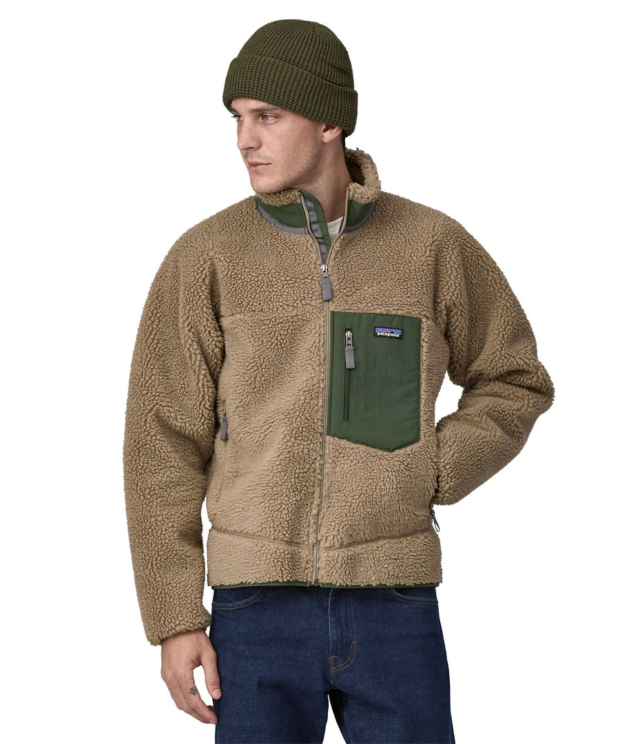 A man wearing a Patagonia Men's Classic Retro-X Jacket in a Seabird Grey colour and a green beanie hat.