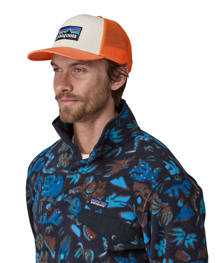 A man wearing a Patagonia Adult P-6 Logo Trucker Hat White Redtail Rust