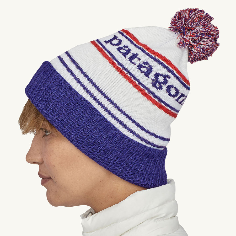 Patagonia Powder Town Beanie Bobble Hat - Park Stripe / Viking Blue. A woman wears the beanie facing sideways against a plain background.