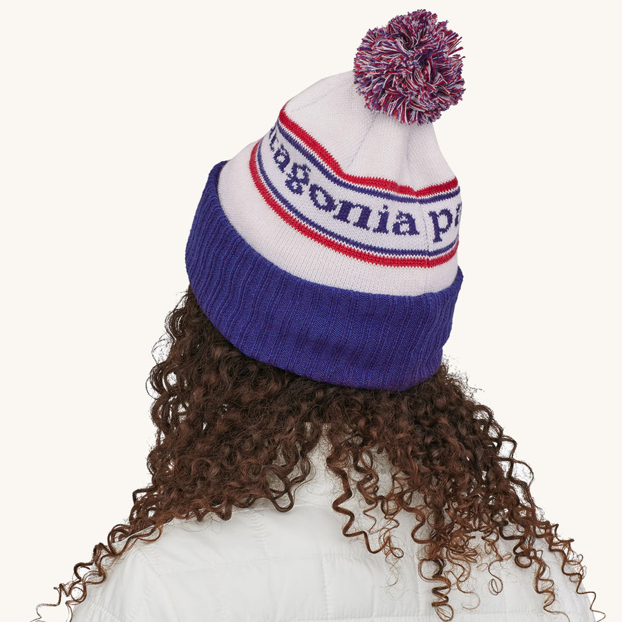 Patagonia Powder Town Beanie Bobble Hat - Park Stripe / Viking Blue. A woman wears the beanie facing away from camera against a plain background.