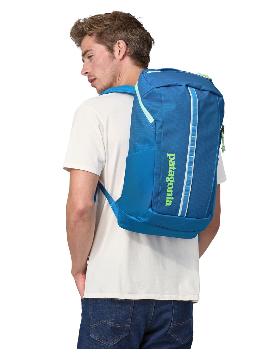 A person carrying the Patagonia Black Hole Recycled Backpack 25L - Vessel Blue on their back and showing the front of the backpack