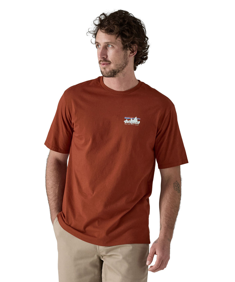 A man wearing the Patagonia Men's 73 Skyline Organic T-Shirt Burnished Red