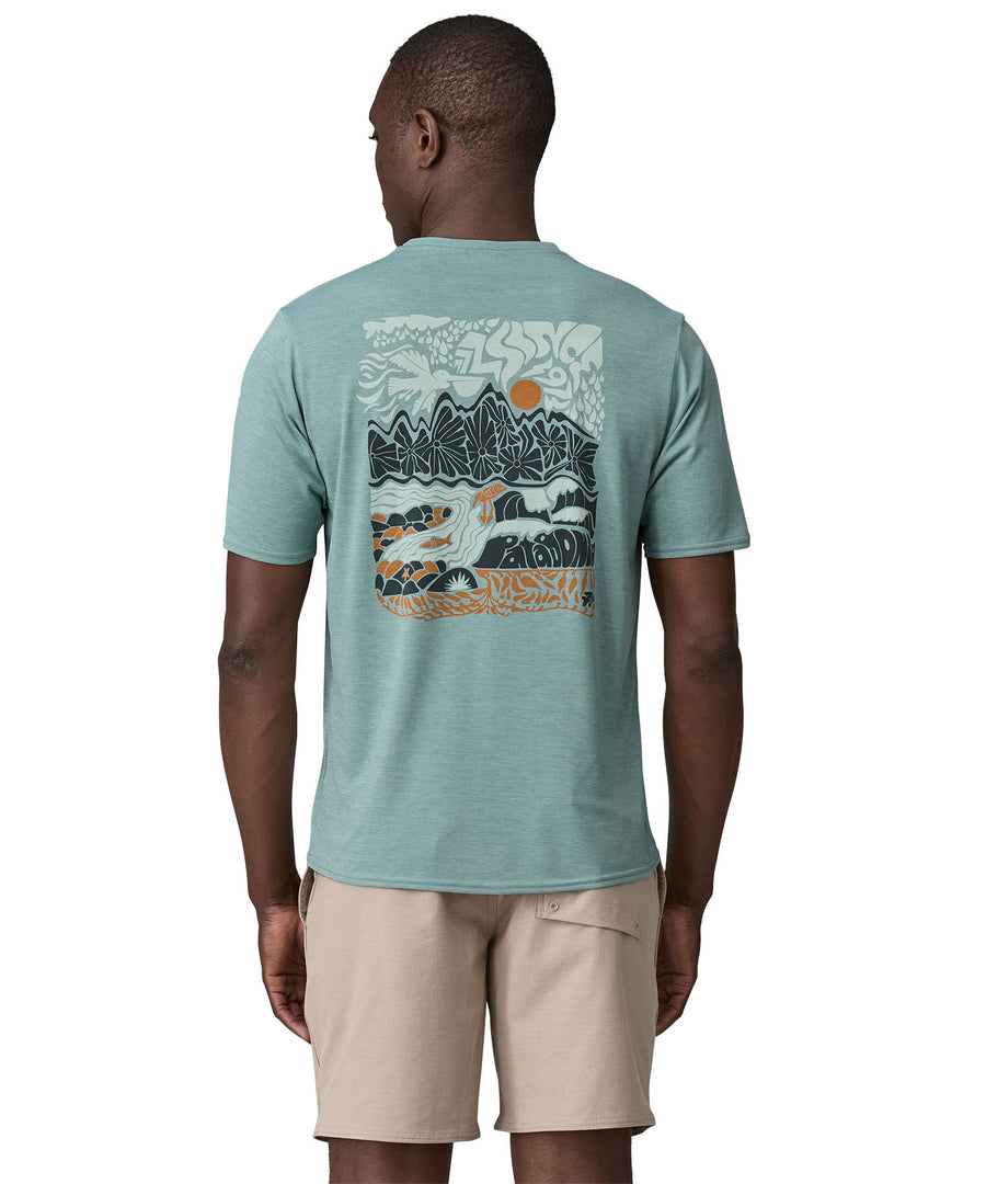 A man wearing a Patagonia Men's Cap Cool Daily Graphic Shirt with a Waters / Thermal Blue design. The man is facing away from the camera showing the back of the t-shirt and the large graphic design. 