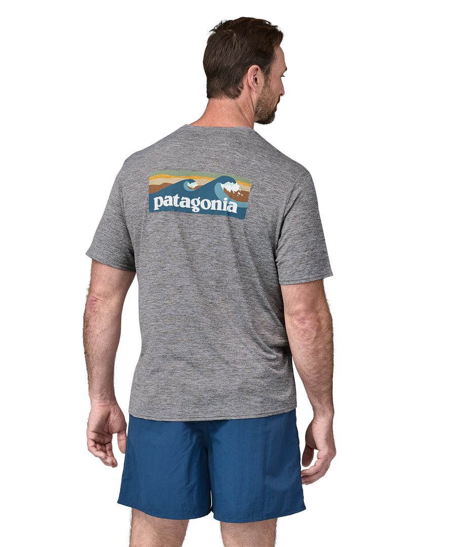 A man wearing a Patagonia Men's Capilene Cool Daily Graphic Shirt with a Waters / Feather Grey design, the man is facing away from the camera showing the back of the t-shirt. 