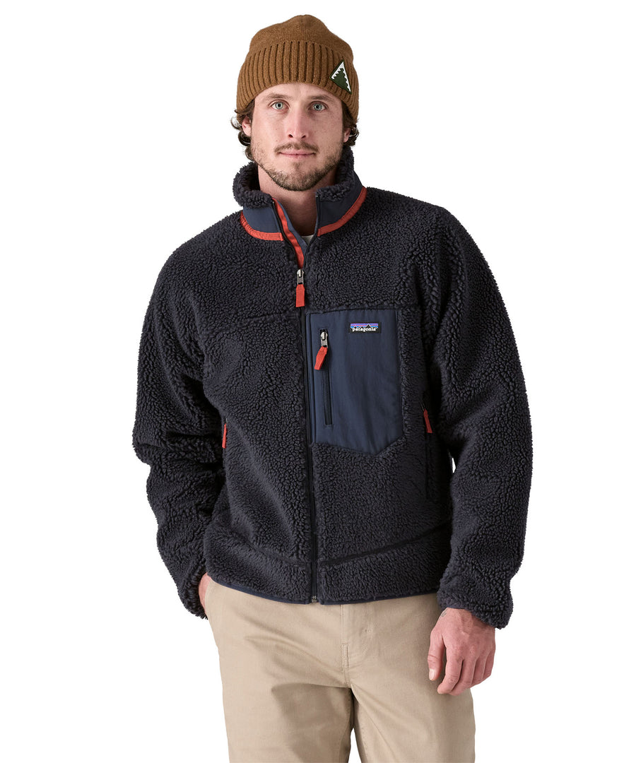 A man wearing a Patagonia Men's Classic Retro-X Jacket in a dark smolder blue colour.  