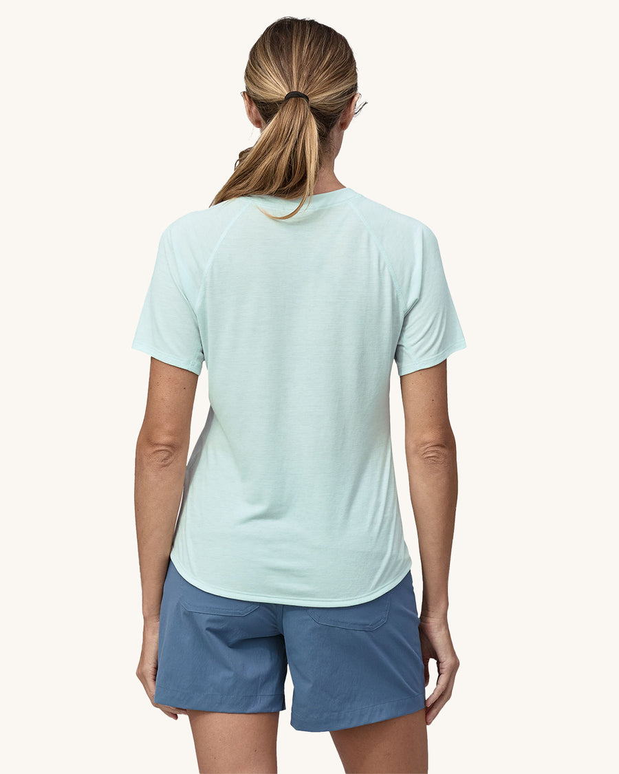 An adult wearing the Patagonia Women's Capilene Cool Trail Graphic Shirt - Forge Mark Crest / Wispy Green