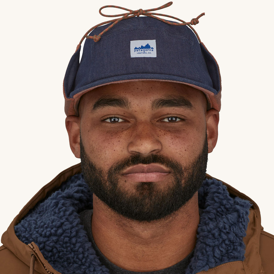 Patagonia Range Earflap Cap - Upriver / Sisu Brown. A man models the front of the cap against a plain background.